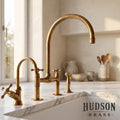 Luxury unlacquered solid brass bridge kitchen faucet with side sprayer, handcrafted in Marrakech by Hudson Brass, featuring a natural living finish patina on a white marble countertop.