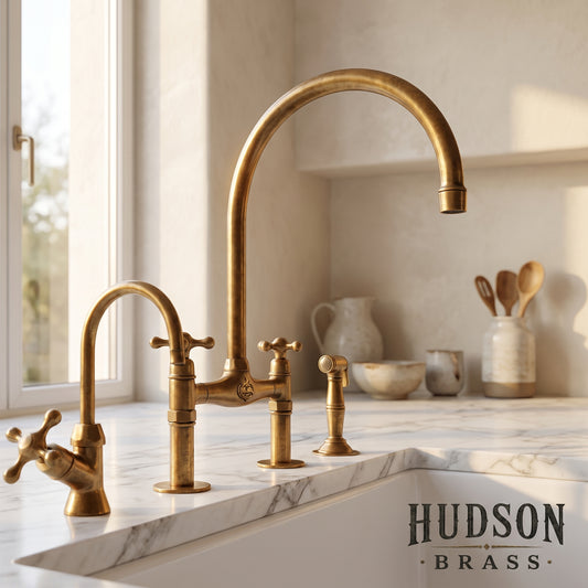 Luxury unlacquered solid brass bridge kitchen faucet with side sprayer, handcrafted in Marrakech by Hudson Brass, featuring a natural living finish patina on a white marble countertop.